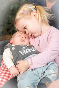 Kuschelfoto Kind mit Baby. Babyhomeshooting von Linz bis Perg