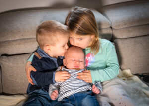 Geschwisterfoto im Wohnzimmer auf der Couch. Babyhomeshooting von Perg bis Amstetten