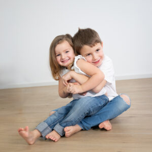 Geschwisterfoto, 2 Kinder beim kuscheln im Studio