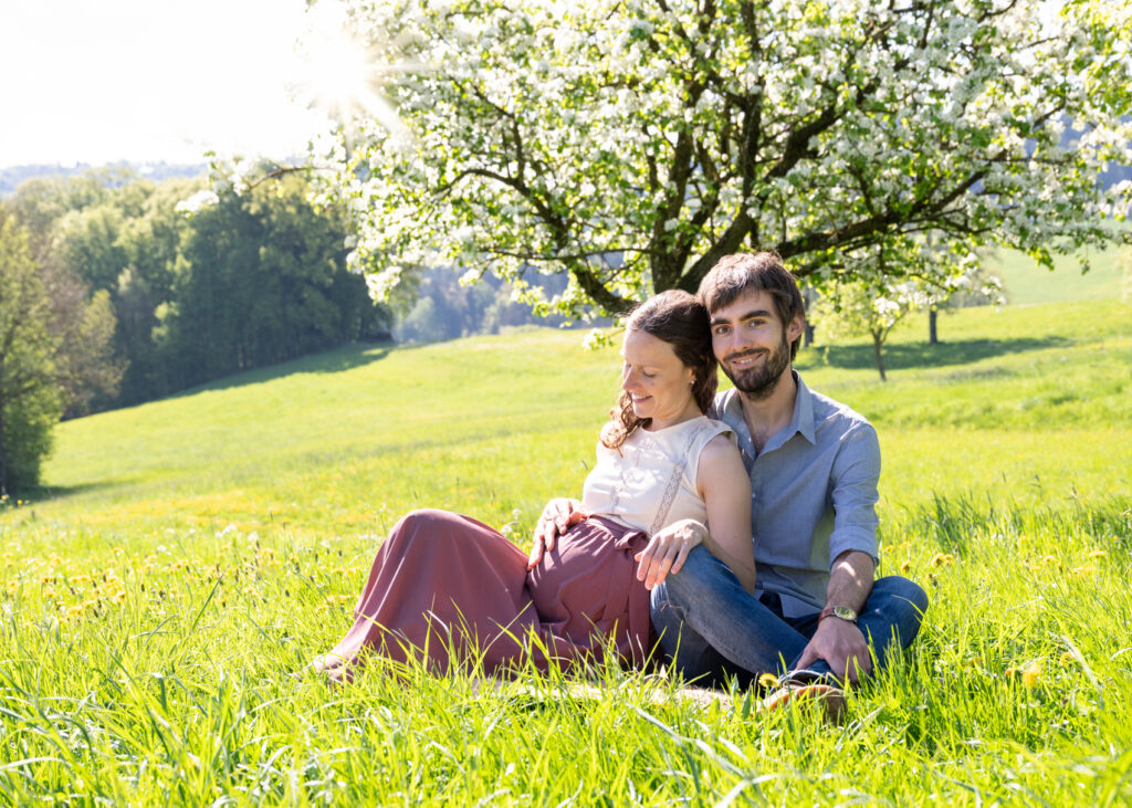 Babybauchshooting outdoor im Frühling. Mama und Papa in der Wiese